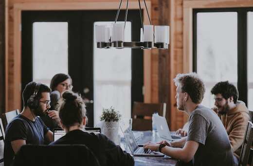 A busy team working at laptops around a table